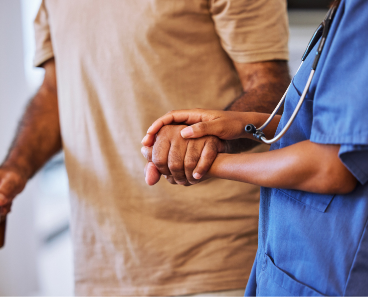 A home care recipient holds the hand of his caregiver.