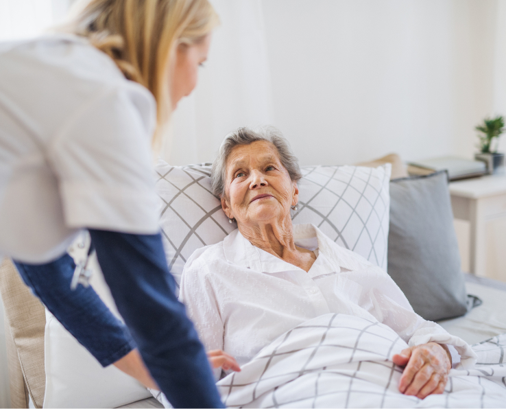 Caregiver greets overnight care recipient as she lays in bed.