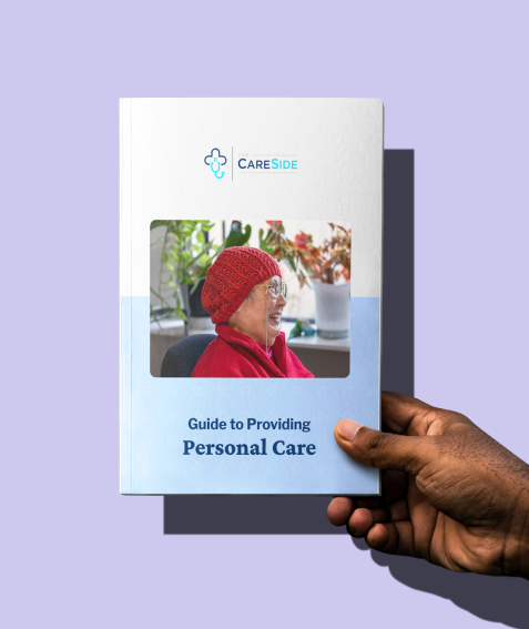 Hand holding The CareSide's guide to Providing Personal Care.