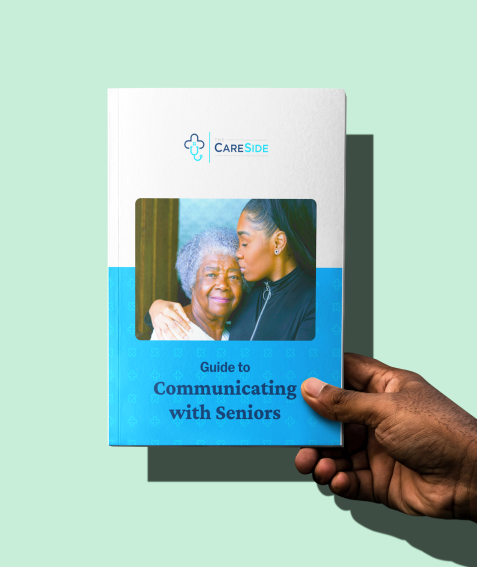 A hand holding The CareSide's guide to Communicating with Seniors.