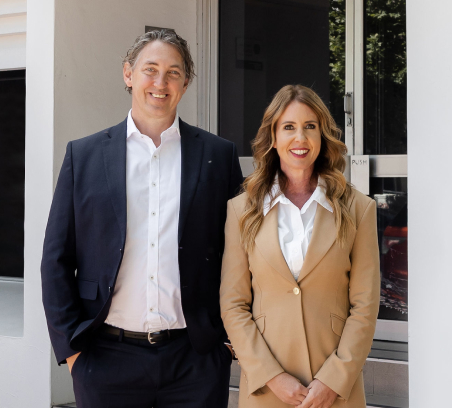 The CareSide's co-founders, Gareth Mahon and Emily Gillett, stand outside while smiling and posing for a photo.