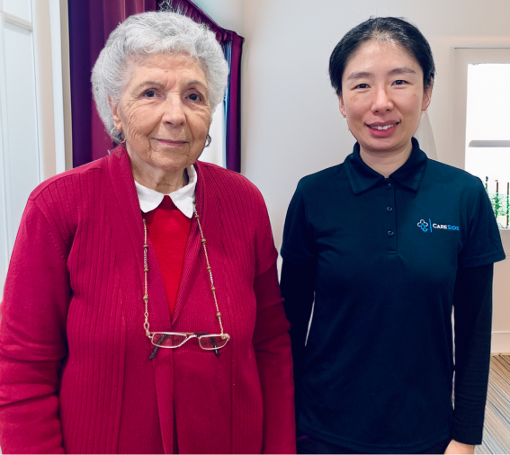 The CareSide client Carla smiles for a photo while standing next to her caregiver, who provides the best home care services for Carla and her family.