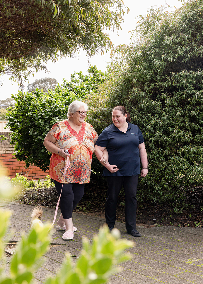 A caregiver from The CareSide provides home care in Darwin while walking alongside her aged care client in the park.