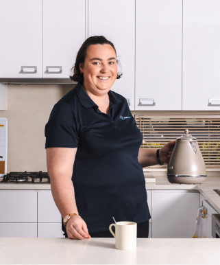 A caregiver from The CareSide smiles for a photo while providing home care services in a kitchen.