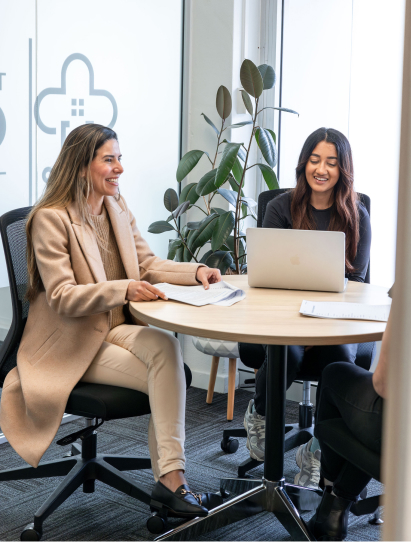 Two aged care professionals from The CareSide team smiling and collaborating at an office.