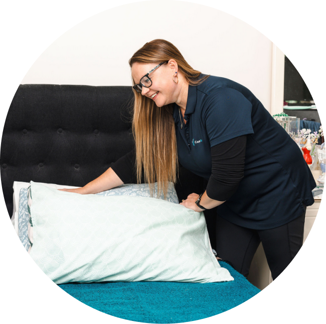 Caregiver from The CareSide makes up a bed for her client while delivering home care in Adelaide.