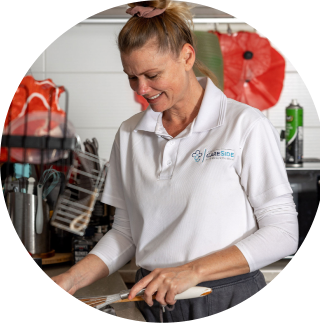 Smiling caregiver from The CareSide provides home care in Darwin while preparing a meal in the kitchen.