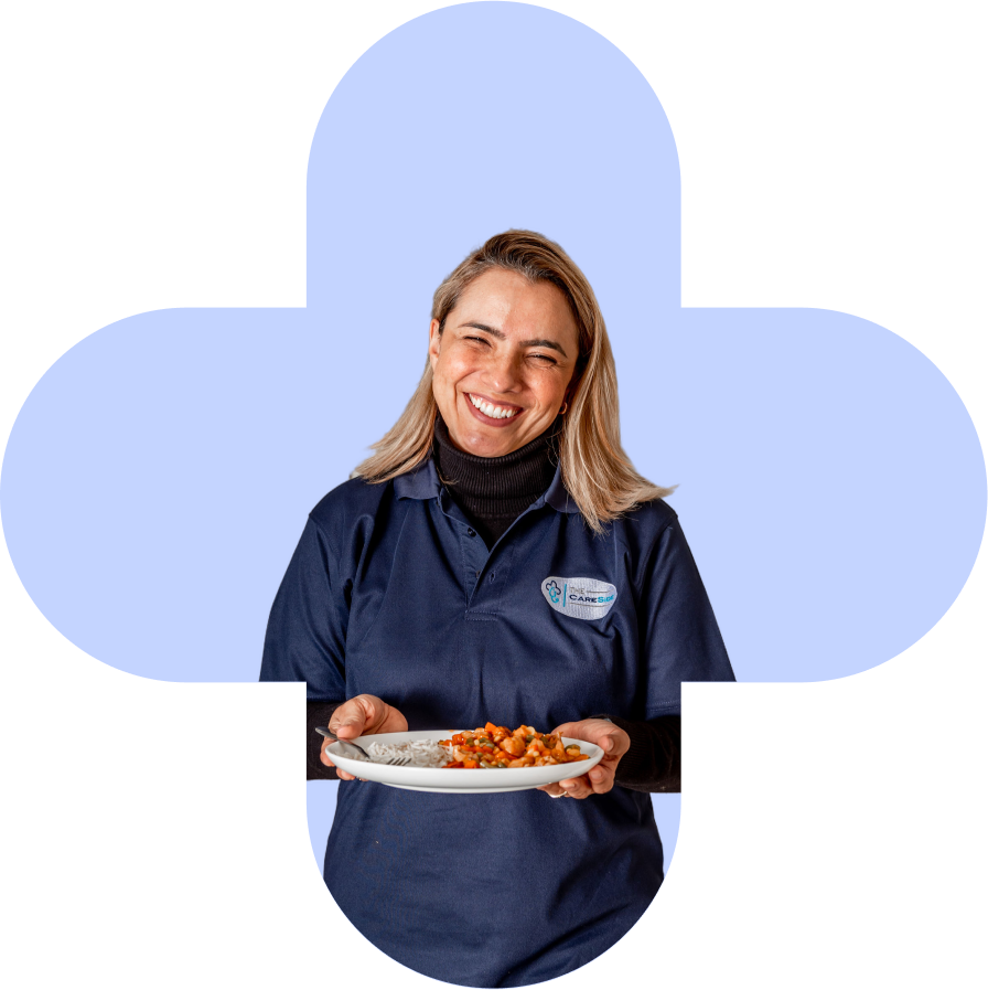 A photo of a caregiver from The CareSide smiling and holding a plate of food.