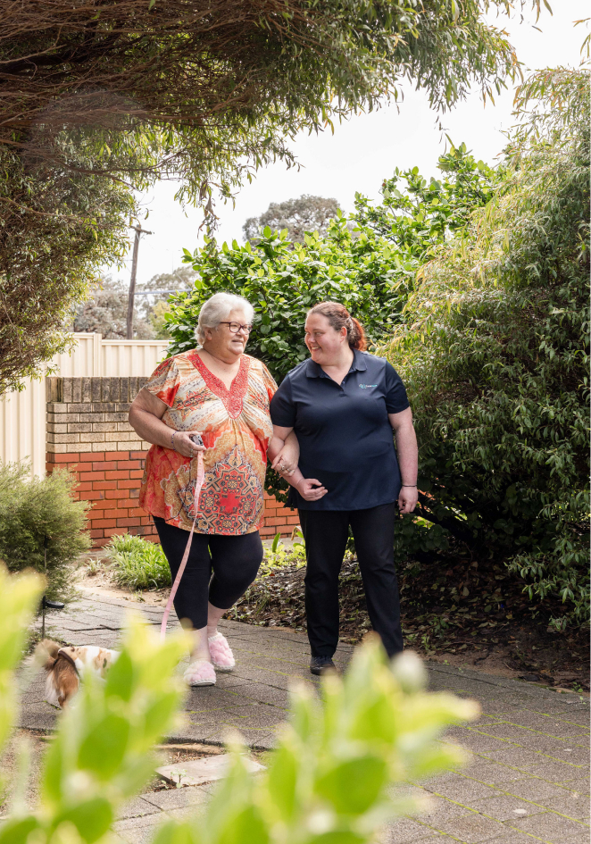 A caregiver from The CareSide provides home care in Melbourne while walking alongside her aged care client in the park.