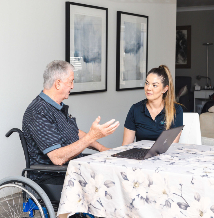 Post-hospital care recipient sitting at a table and talking with his caregiver.