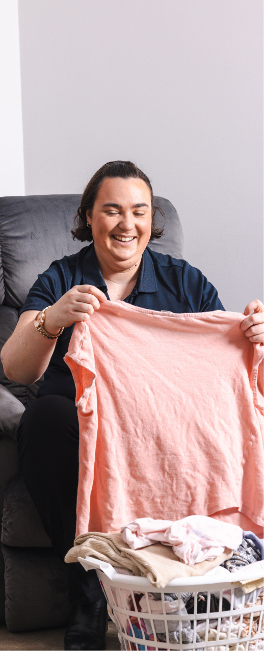 A caregiver from The CareSide smiles while folding laundry and providing home care support.