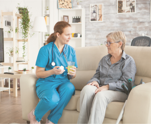 Registered nurse has a conversation with her home care client while they sit next to each other on a sofa.