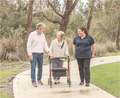 Home care recipients enjoy a walk outside alongside their smiling caregiver from The CareSide.