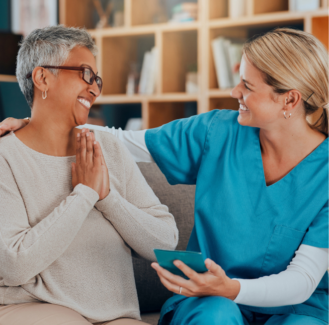 Happy nursing care recipient smiles while looking at her friendly nurse.