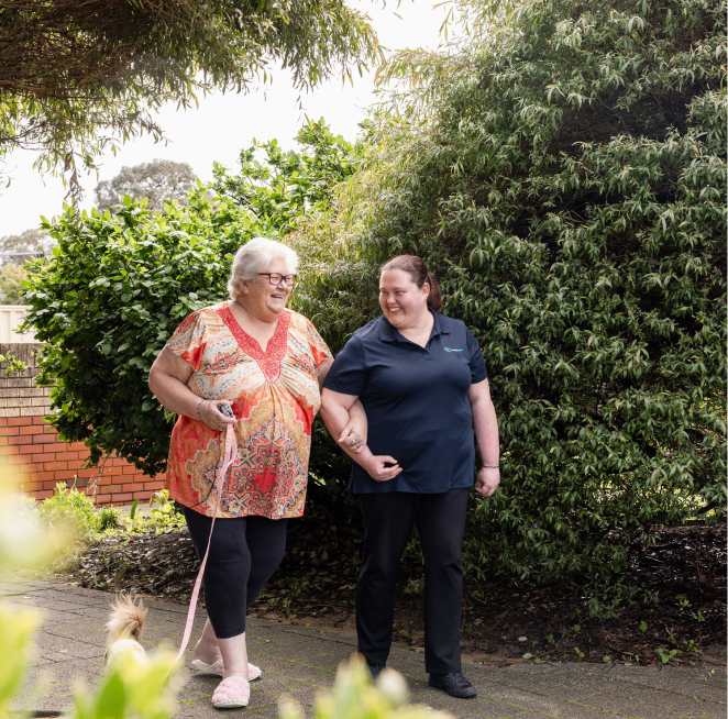 A companion caregiver from The CareSide alongside her happy client as they enjoy a walk together outside.