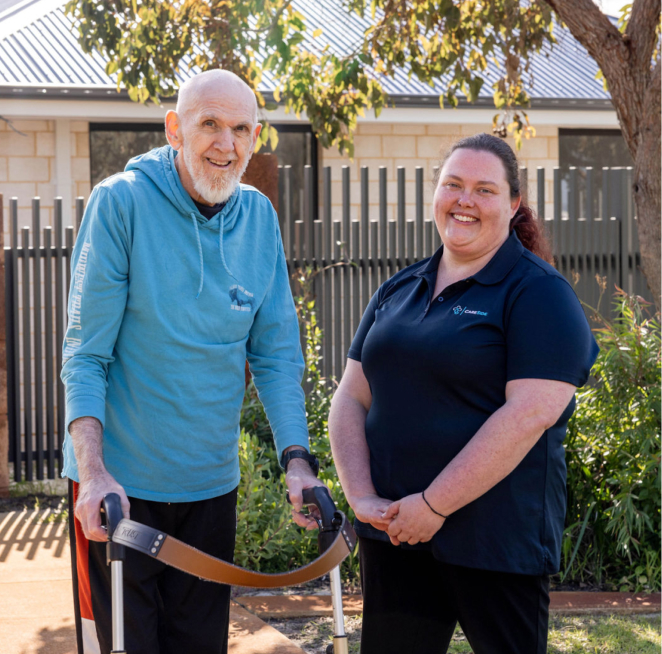 24-hour home care recipient stands outside next to his smiling caregiver from The CareSide.