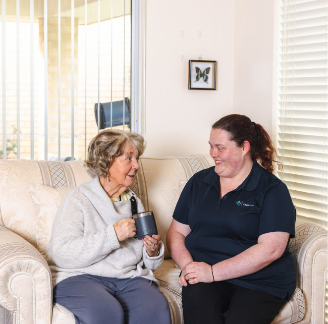 Home care recipient sitting on a sofa next to her caregiver from The CareSide.