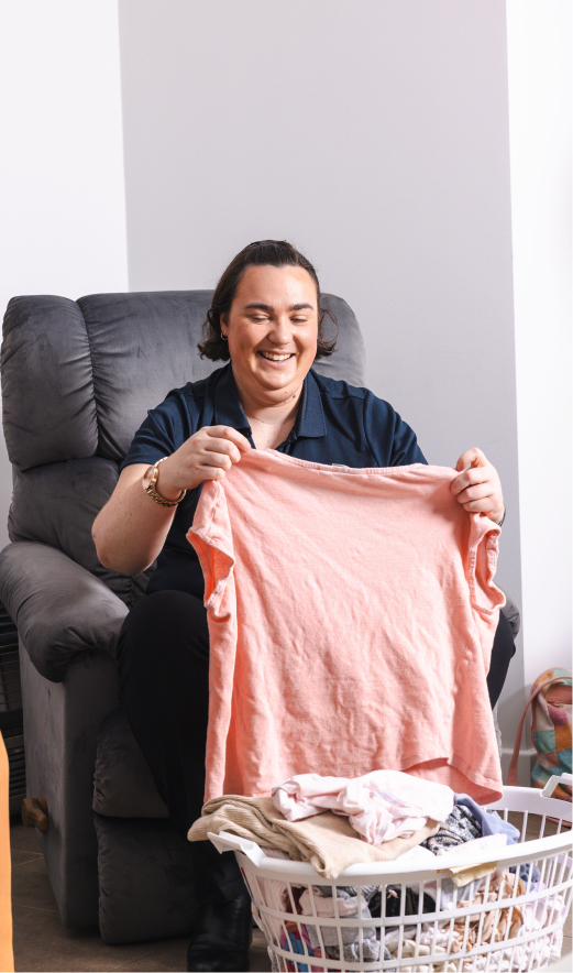 Live-in caregiver from The CareSide smiles while folding laundry.