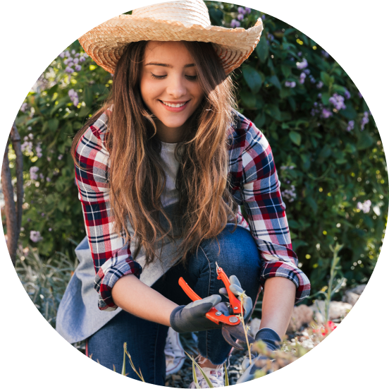 Young woman smiles while gardening outside.