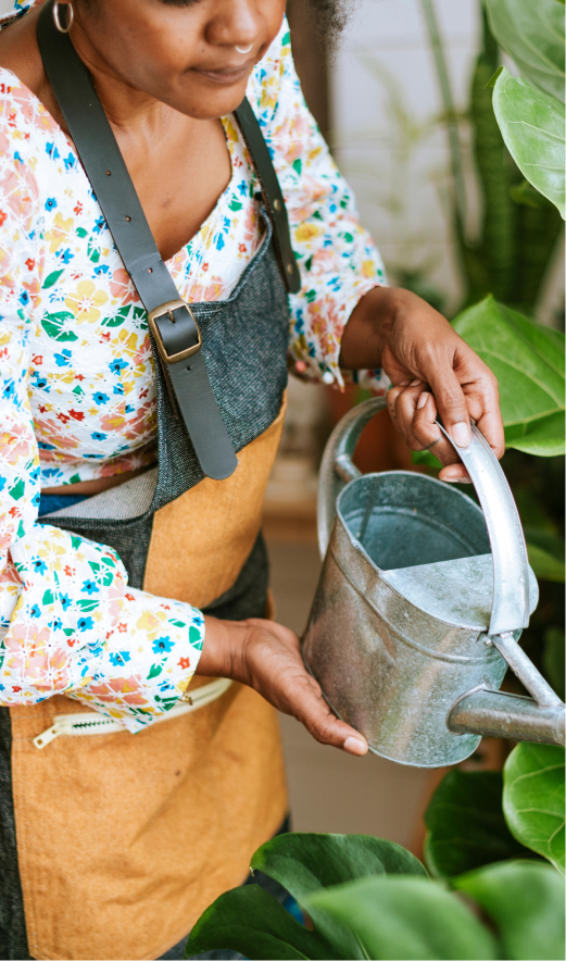 Photo of a woman watering plants and completing gardening tasks.